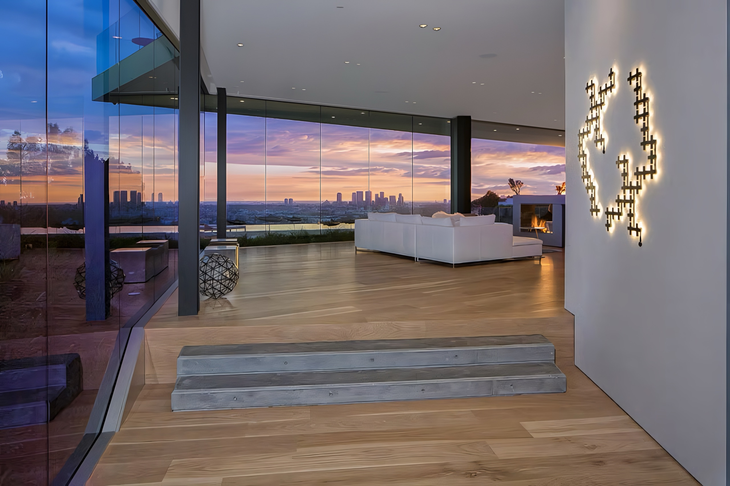 A glass-walled living room above Los Angeles at sunset
